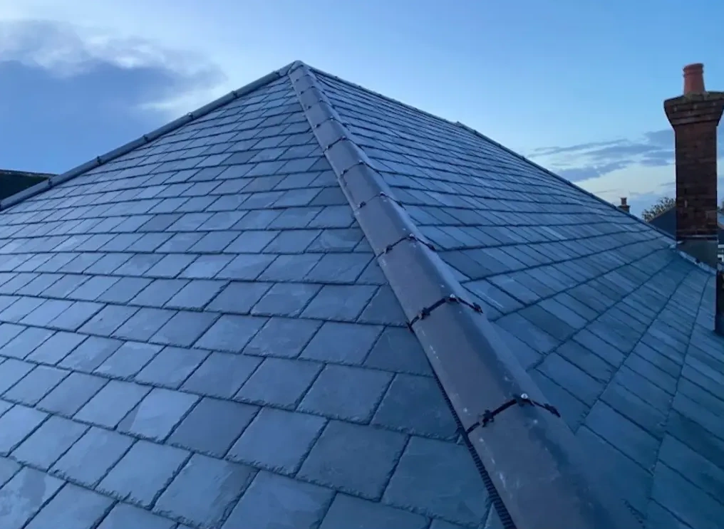 Completed natural slate roof replacement with ridge and chimney