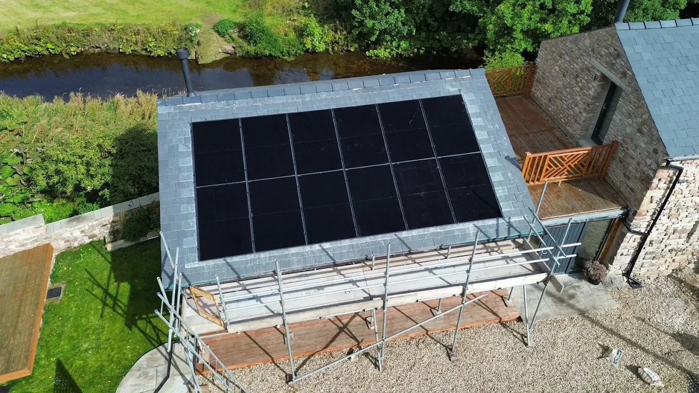 Aerial view of solar panels fitted to a slate roof beside a river