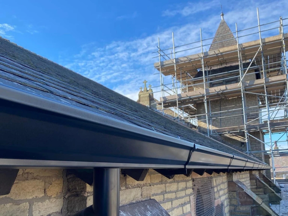 Black uPVC downpipe and guttering installed on a stone building
